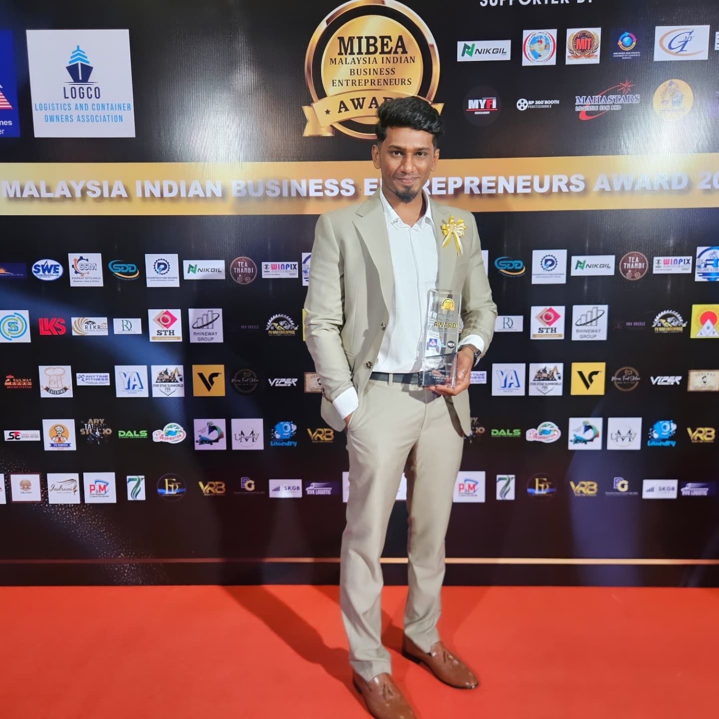 Tea Thambi founder holding the MIBEA 2025 trophy on the red carpet